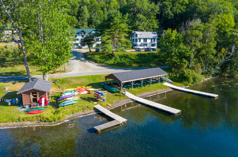 An aerial view of a boathouse and docks in front of a lake.