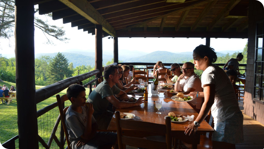 A group of people seated at a dining area on a porch.