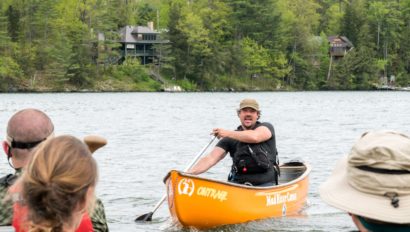 A man in a canoe speaking to a group.