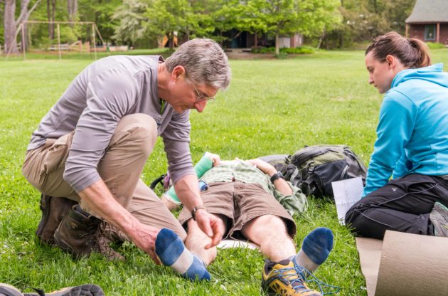 A man examine's another person's leg for a first aid course.