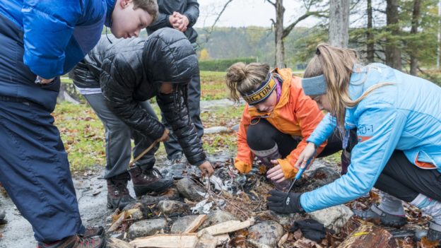A group of campers gathered around a fire pit.