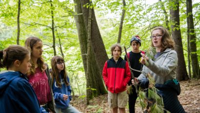 An instructor showing students a tree branch.