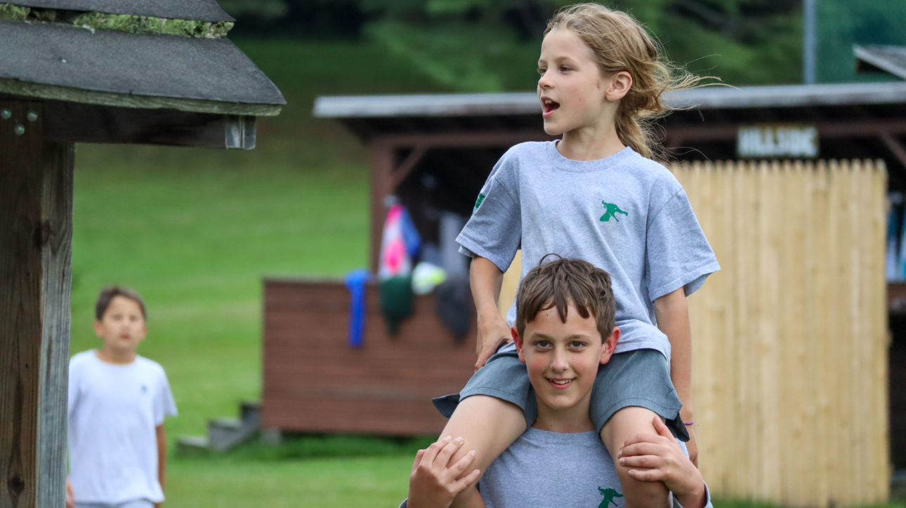 A camper sitting on another camper's shoulders.