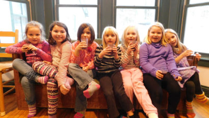Seven children smiling and packed onto one couch.