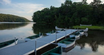 A bunch of row boats next to the docks on the lake.