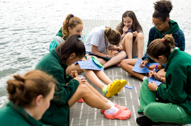 A group of Aloha campers sitting and drawing on the docks.