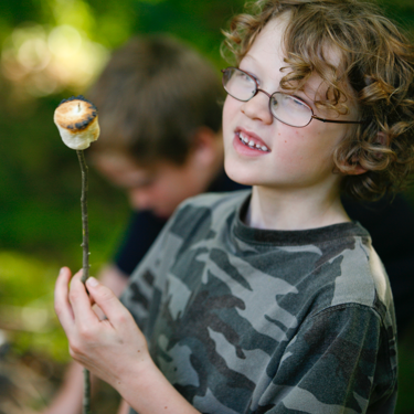 A horizons camper with a roasted marshmallow on a stick.