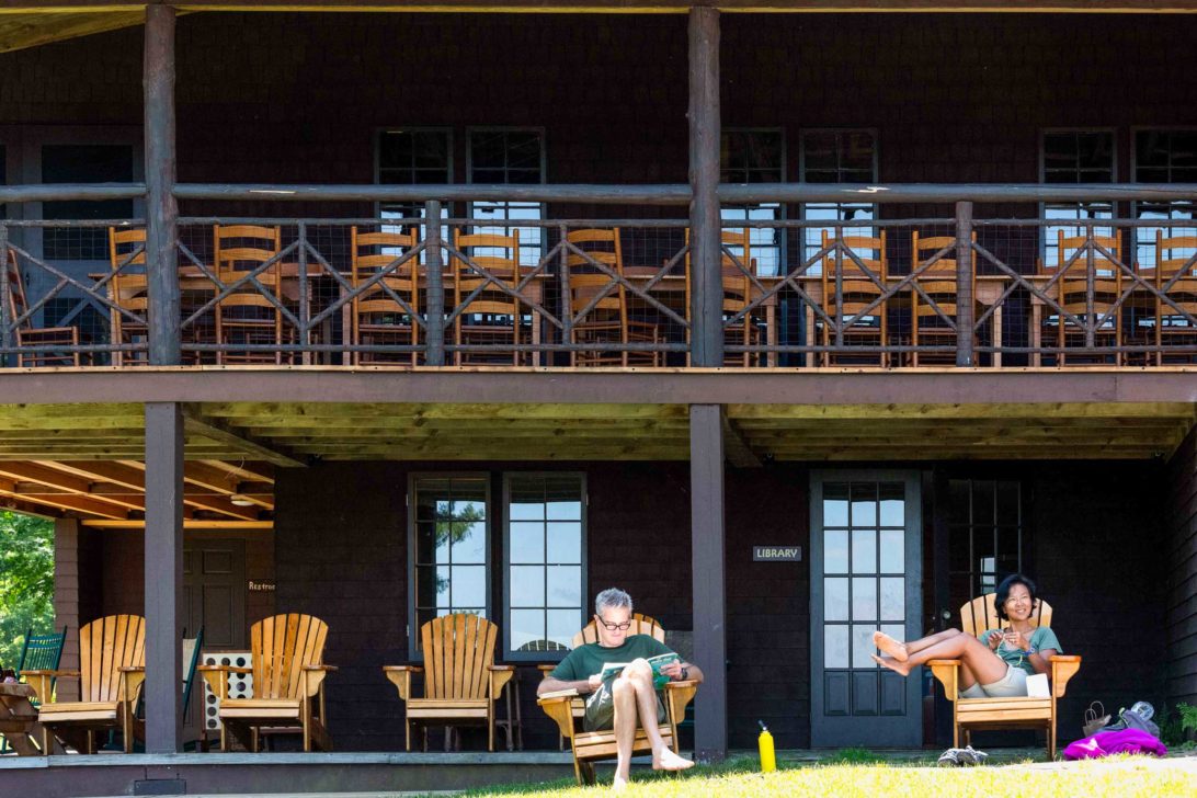 Two people relaxing on lawn chairs in front of a lodge.